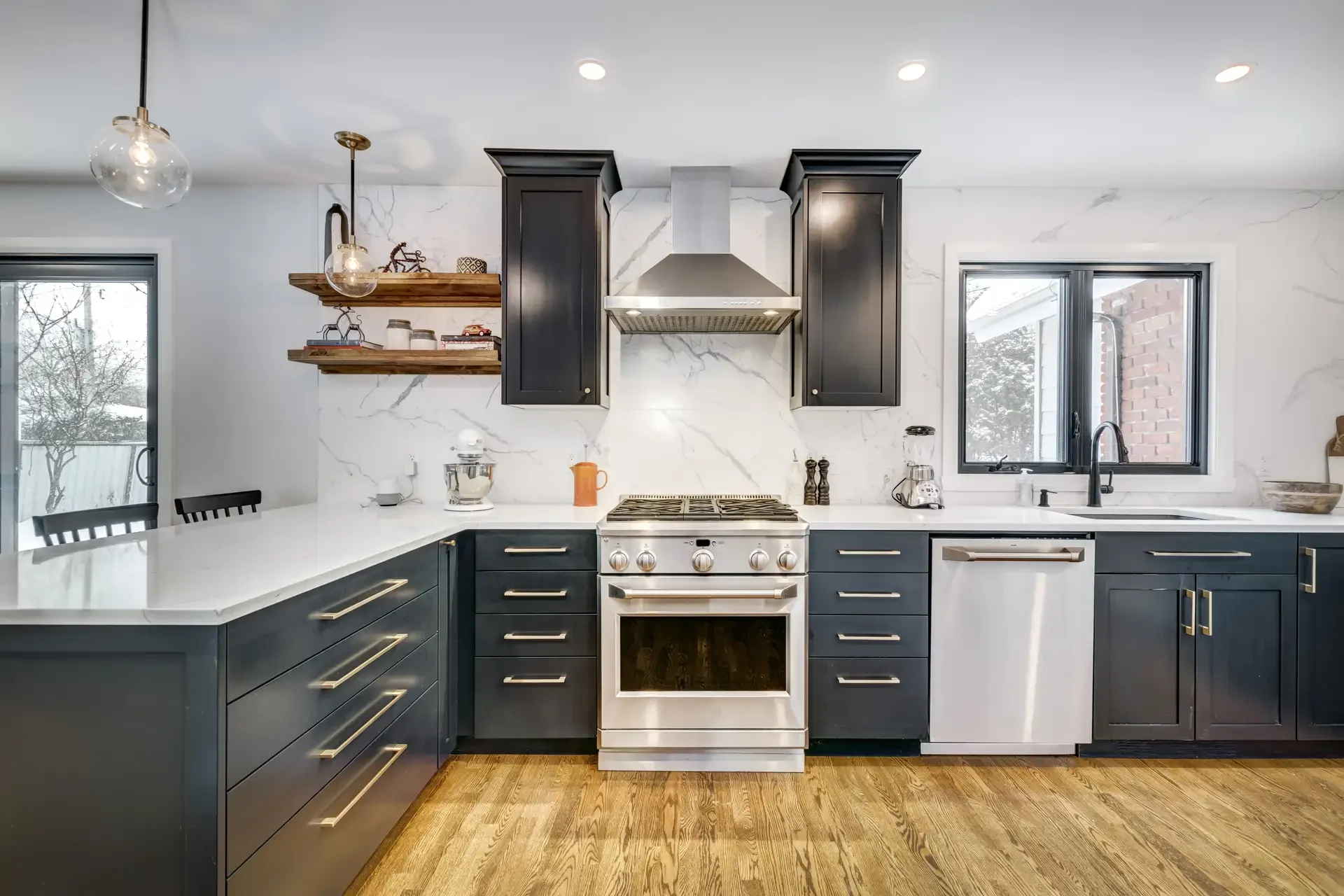 Modern kitchen with stainless steel oven, gas cooktop, range hood, dishwasher, and countertop appliances in pristine condition