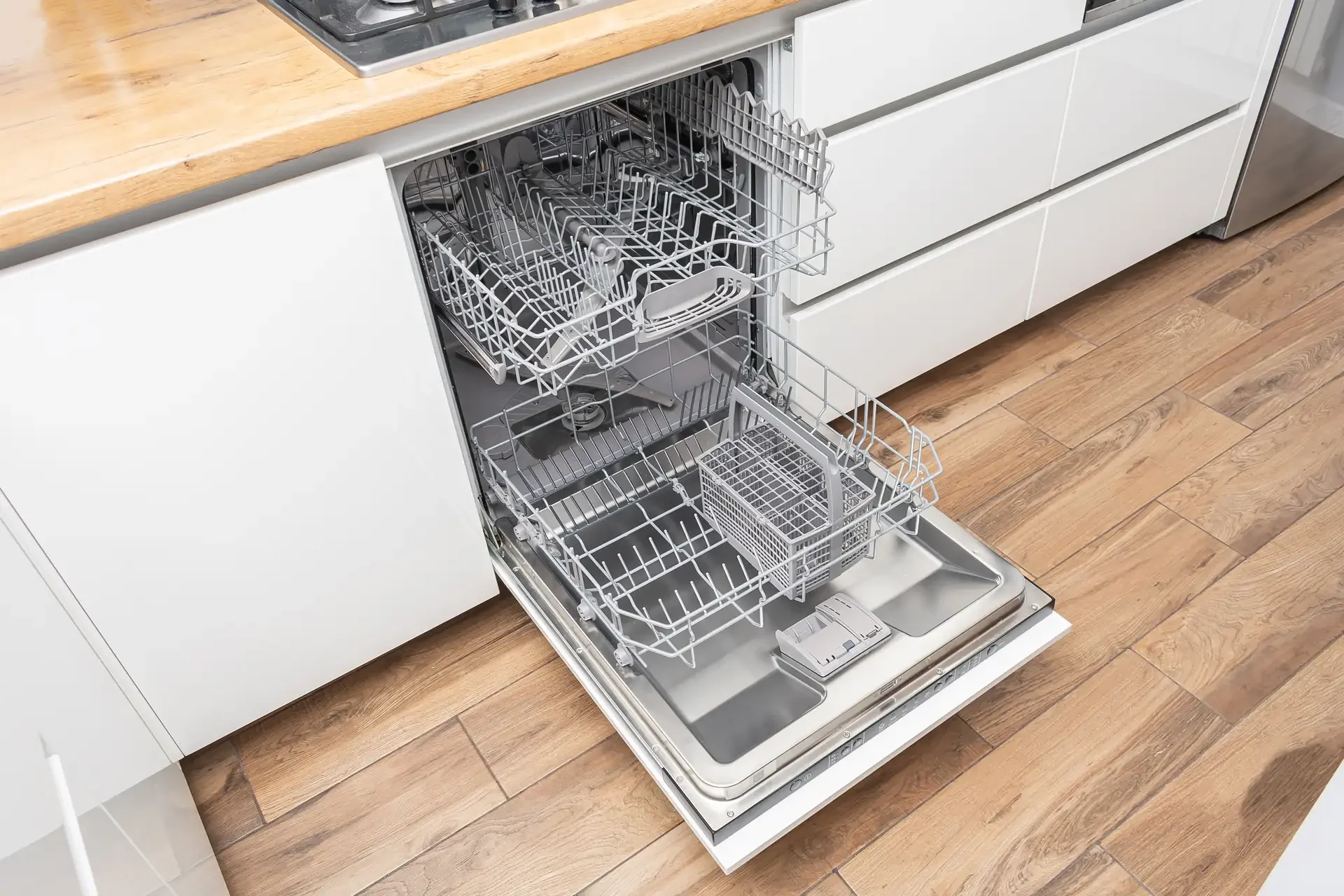 Modern built-in dishwasher with open door showing empty upper and lower racks in contemporary kitchen setting