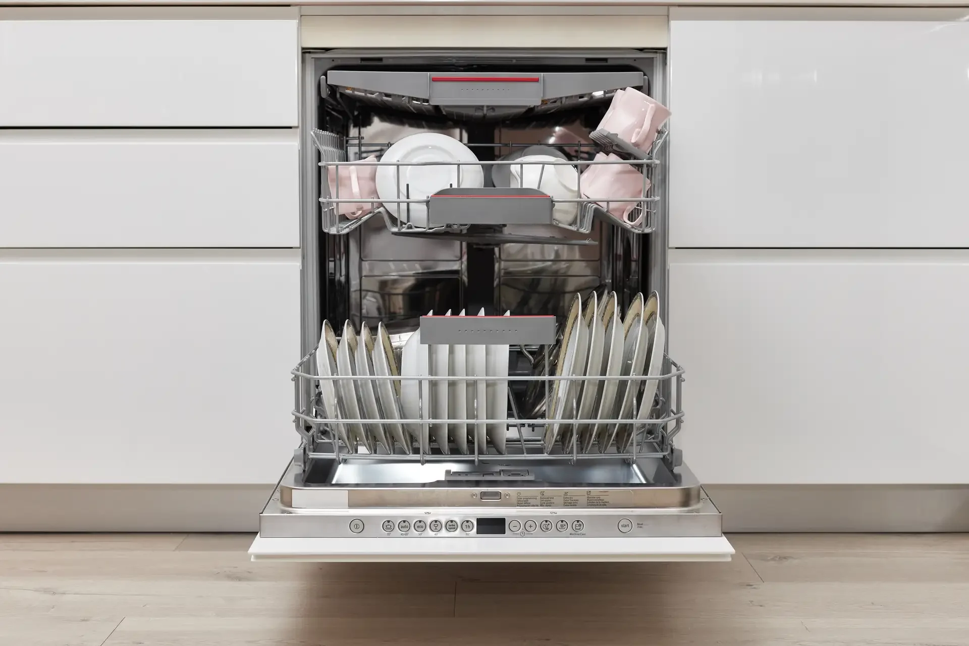 Modern built-in dishwasher with open door showing clean dishes loaded on racks and visible control panel