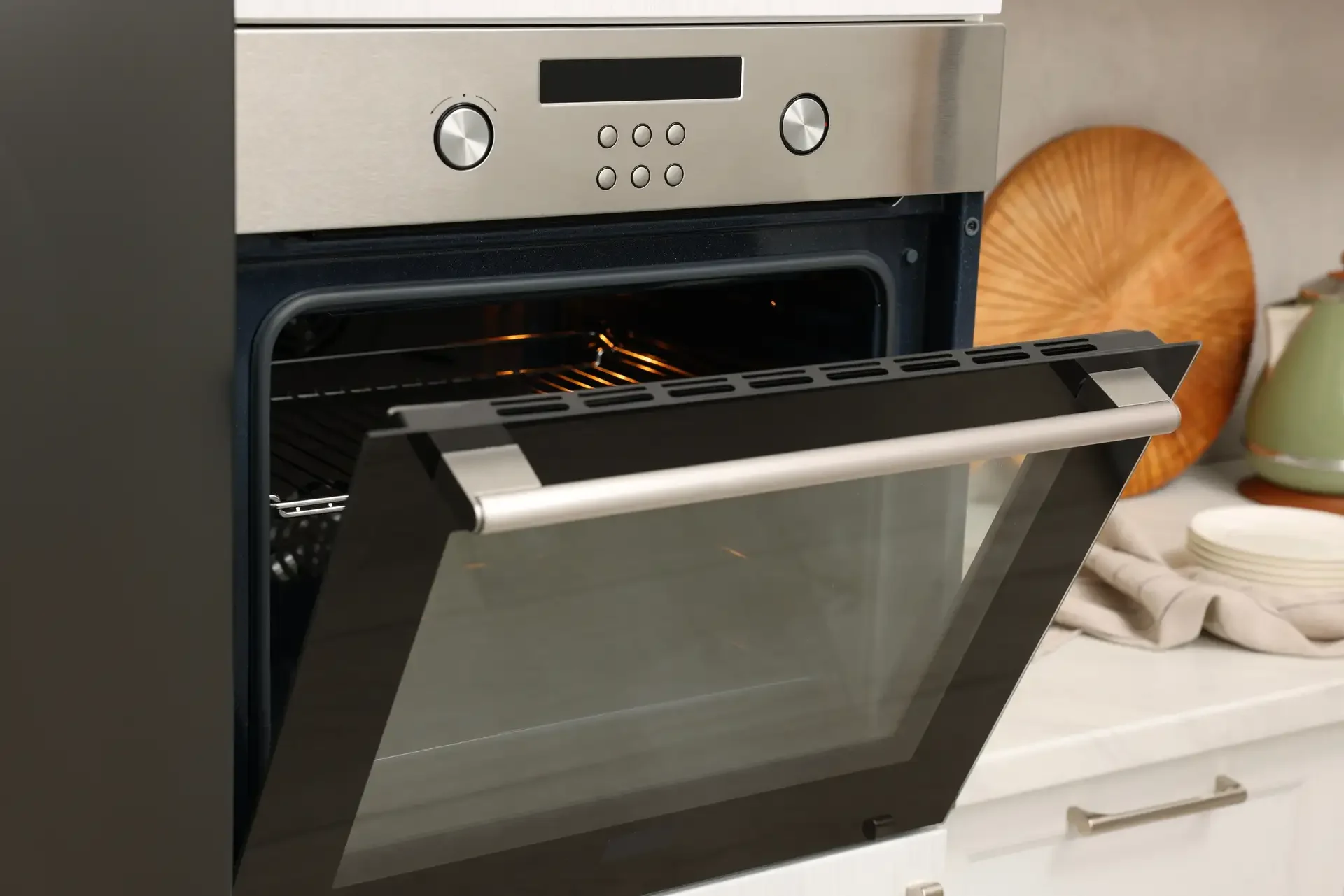 Modern built-in electric oven with open door showing illuminated interior and clean oven racks in contemporary kitchen setting